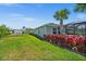 Lush backyard featuring a screened-in patio with hot tub and vibrant red landscaping, perfect for outdoor enjoyment at 17459 Palmetto Pass Ln, Punta Gorda, FL 33982