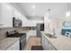 Bright kitchen features granite countertops, stainless steel appliances, white cabinetry, and a center island with a sink at 17459 Palmetto Pass Ln, Punta Gorda, FL 33982