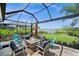 Relaxing screened patio with seating around a fire pit offering serene water views and lush landscaping at 17459 Palmetto Pass Ln, Punta Gorda, FL 33982