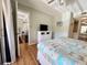 Cozy bedroom with hardwood floors, dresser with TV, and a glimpse into the living area at 19505 Quesada Ave # Ii201, Port Charlotte, FL 33948
