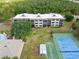 A beautiful aerial of complex buildings, tennis courts, pool, shuffleboard, and well-maintained green spaces at 1999 Kings Hwy # 24C, Punta Gorda, FL 33980