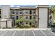 Exterior view of condo building with tropical landscaping, parking, and private balconies for each unit at 1999 Kings Hwy # 24C, Punta Gorda, FL 33980