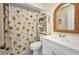 Cozy bathroom with a sunflower shower curtain, white vanity, and a decorative wicker-framed mirror at 20355 Mount Prospect Ave, Port Charlotte, FL 33952