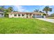 Charming single-story home featuring a well-kept lawn, neutral colors and a paved driveway leading to a garage at 20355 Mount Prospect Ave, Port Charlotte, FL 33952