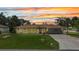 Charming home boasts a well-maintained lawn and a neutral color scheme under a colorful sunset sky at 20355 Mount Prospect Ave, Port Charlotte, FL 33952