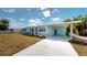 Quaint single-story home with a covered carport, blue door, stone accents, and mature landscaping at 20407 Albury Dr, Port Charlotte, FL 33952