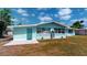 Rear view of a single-story home with a blue door, well-maintained landscaping, and a concrete patio at 20407 Albury Dr, Port Charlotte, FL 33952