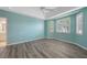 Bedroom featuring wood-look floors, light-blue walls, a ceiling fan, and white-trimmed windows at 2087 Lynx Run, North Port, FL 34288