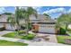 A charming villa displays a brick driveway leading to a two-car garage, complemented by lush landscaping and mature palm trees at 2087 Lynx Run, North Port, FL 34288