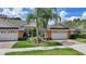 A charming villa displays a brick driveway leading to a two-car garage, complemented by lush landscaping and mature palm trees at 2087 Lynx Run, North Port, FL 34288