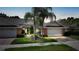 A charming villa displays a brick driveway leading to a two-car garage, complemented by lush landscaping and mature palm trees at 2087 Lynx Run, North Port, FL 34288