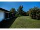 Wide backyard view showing the screened-in porch and a grassy expanse with mature trees, enhancing the home's appeal at 2113 Barksdale St, Port Charlotte, FL 33948