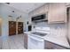 Modern kitchen featuring gray cabinets, white appliances, and seamless transition to the living room at 2113 Barksdale St, Port Charlotte, FL 33948
