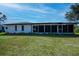 Rear view of the home featuring a long, screened-in porch that enhances outdoor living at 2113 Barksdale St, Port Charlotte, FL 33948