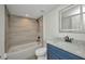 Bathroom featuring a bathtub and shower combination with grey tile and a blue vanity with a marble countertop at 23465 Harborview Rd # 1002, Punta Gorda, FL 33980