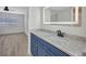 Bathroom featuring a blue vanity, illuminated mirror, and a shower with white tile at 23465 Harborview Rd # 1002, Punta Gorda, FL 33980