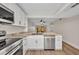 Modern kitchen features white cabinets, stainless steel appliances, and granite countertops with a view to the living area at 23465 Harborview Rd # 1002, Punta Gorda, FL 33980