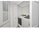Laundry room with front loading washer and dryer, white storage cabinet and plantation shutters on the window at 23465 Harborview Rd # 1002, Punta Gorda, FL 33980