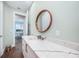 Bathroom with marble counter, round mirror, and view into adjacent dining room with chandelier at 25273 Paraguay St, Punta Gorda, FL 33983