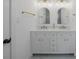 Bright bathroom featuring double sinks, gold fixtures, and modern lighting at 27385 Voyageur Dr, Punta Gorda, FL 33983
