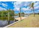 Private wooden dock, offering a tranquil waterfront setting, complemented by lush greenery and blue sky at 27385 Voyageur Dr, Punta Gorda, FL 33983