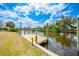 Exterior view of a private canal dock with a wood deck and grassy lawn at 27385 Voyageur Dr, Punta Gorda, FL 33983