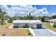 Beautiful one-story home featuring a manicured lawn, grey exterior, and a pristine white metal roof at 27385 Voyageur Dr, Punta Gorda, FL 33983
