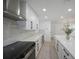 Updated kitchen featuring white cabinetry, island, stainless steel appliances, and modern range hood at 27385 Voyageur Dr, Punta Gorda, FL 33983