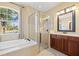 Bathroom with a glass-enclosed shower, tub, and vanity with decorative mirror at 2871 Suncoast Lakes Blvd, Punta Gorda, FL 33980