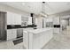 An open kitchen with white cabinets, a large island, stainless steel appliances, and black subway tile backsplash at 3544 Monfero Ave, North Port, FL 34286