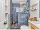 Stylish renovated bathroom featuring blue tiled shower, unique wooden stool and modern fixtures at 3927 Vasco St, Punta Gorda, FL 33950