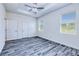 Bright bedroom featuring two windows, grey wood floors, a tray ceiling, and a modern ceiling fan at 4285 Oak Terrace Cir, Port Charlotte, FL 33953