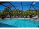Inviting screened-in pool area featuring a sparkling pool, lounge chairs, and lush landscaping at 4339 Boggs St, Port Charlotte, FL 33948