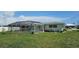 Backyard view of the home with a screened-in pool enclosure, lush lawn, and landscaping at 570 Mimosa Nw Ave, Port Charlotte, FL 33952