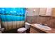 Bathroom with tropical shower curtain, tile, and light fixture at 570 Mimosa Nw Ave, Port Charlotte, FL 33952