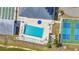 Aerial view of community pool with lounge chairs, umbrellas, nearby shuffleboard courts, and tennis courts at 6144 Redwing Ave, Englewood, FL 34224