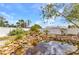 Landscaped backyard boasts a serene pond with rock features and a relaxing bench for enjoying the view at 6753 Thorman Rd, Port Charlotte, FL 33981