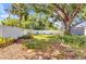 Backyard features a lush green lawn, mature shade trees, and a white picket fence at 6753 Thorman Rd, Port Charlotte, FL 33981