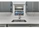 Kitchen features a stainless steel sink, gray cabinets, hexagon backsplash tiles and white countertops at 6753 Thorman Rd, Port Charlotte, FL 33981