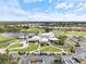 Aerial view of a community clubhouse surrounded by lush landscaping, a golf course, and a lake at 857 Macaw Cir, Venice, FL 34285