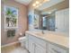 Bright bathroom featuring a white vanity, granite countertop, window, and glass shower at 857 Macaw Cir, Venice, FL 34285