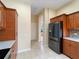 Kitchen with tile floors, stainless steel refrigerator and warm wood cabinets at 857 Macaw Cir, Venice, FL 34285