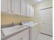 Functional laundry room with cabinets, a utility sink, a washer, and a dryer at 857 Macaw Cir, Venice, FL 34285