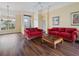 Bright living room featuring hardwood floors, natural light, and comfortable red sofa set at 857 Macaw Cir, Venice, FL 34285