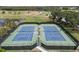 Aerial view of well-maintained tennis courts with green and blue surfaces, set against a lush green landscape with surrounding trees at 857 Macaw Cir, Venice, FL 34285