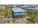 Beautiful blue elevated beach house showcasing wood decks, a metal roof, and lush tropical surroundings at 9390 Little Gasparilla Island, Placida, FL 33946