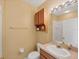 Bathroom with a white toilet, sink, and a wood cabinet above the toilet at 1215 Jonah Dr, North Port, FL 34289
