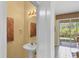 Powder room with pedestal sink, decorative mirror, and view to the lanai at 1215 Jonah Dr, North Port, FL 34289