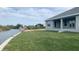 Expansive backyard with fresh green lawn, access to a canal, and the home's gray exterior with covered porch at 13236 Pace Cir, Port Charlotte, FL 33981