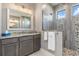 This bathroom features a walk-in stone shower, gray vanity, large mirror, and is brightly lit at 1330 Mineo Dr, Punta Gorda, FL 33950
